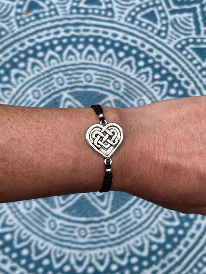 Celtic heart charm on macrame bracelet band with bead stoppers on wrist with mandala background