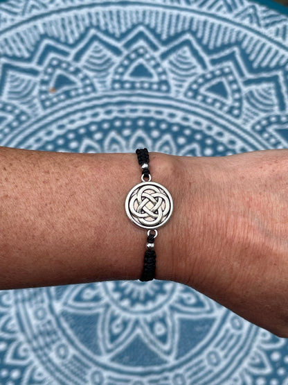 Celtic knot charm on macrame bracelet band with bead stoppers on wrist with mandala background