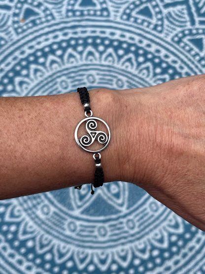 Celtic try charm on macrame bracelet band with bead stoppers on wrist with mandala background