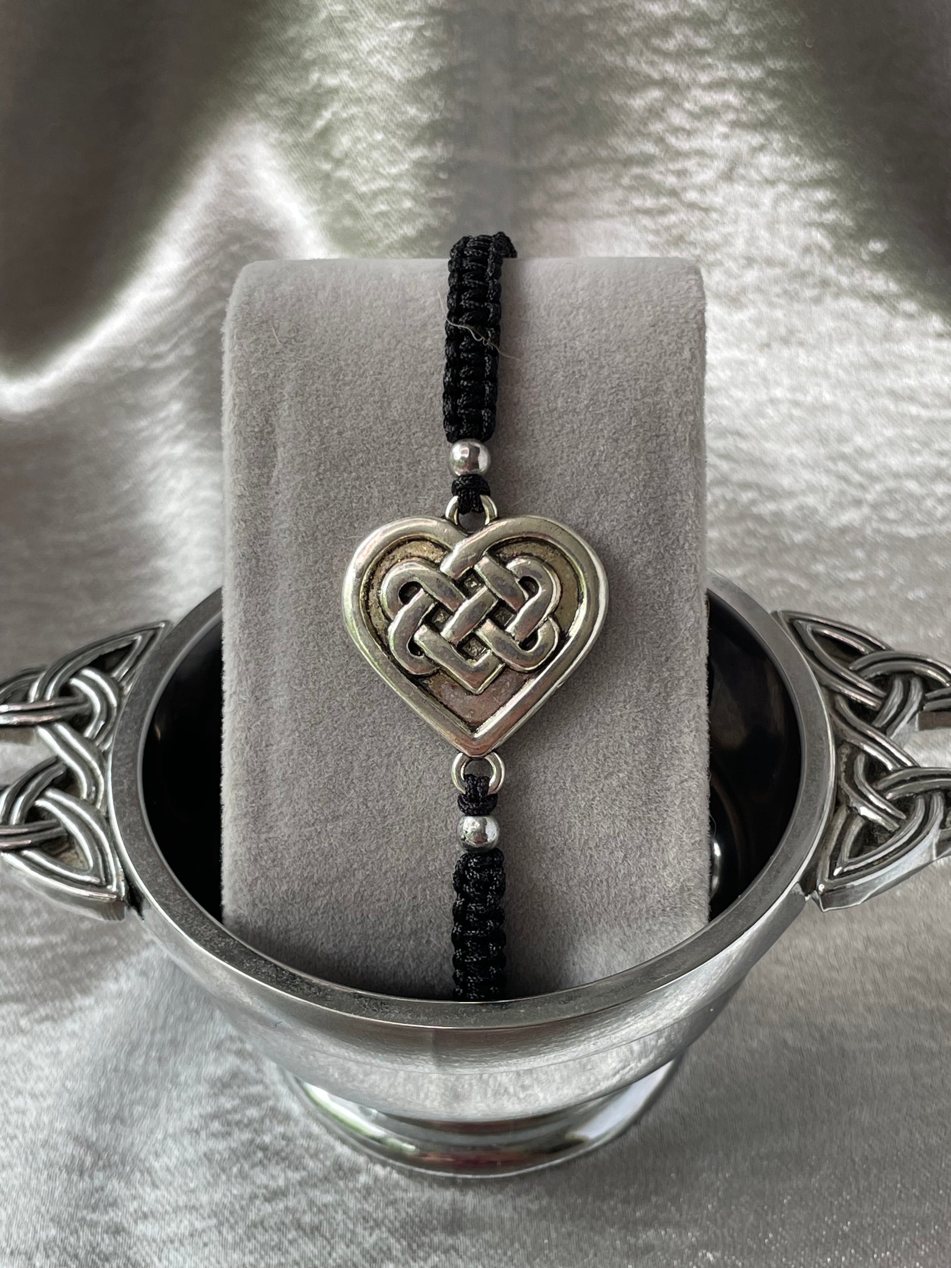 Celtic heart charm on macrame bracelet band with bead stoppers close up placed on bracelet stand in silver quaiche