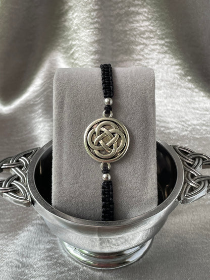 Celtic knot charm on macrame bracelet band with bead stoppers close up placed on bracelet stand in silver quaiche