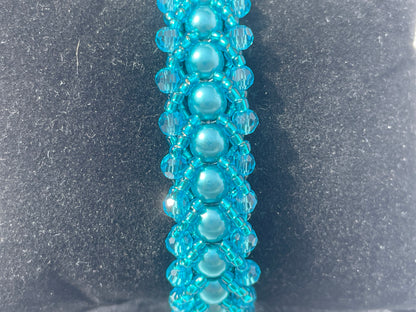 Close up of teal pearl and crystal bracelet on black background