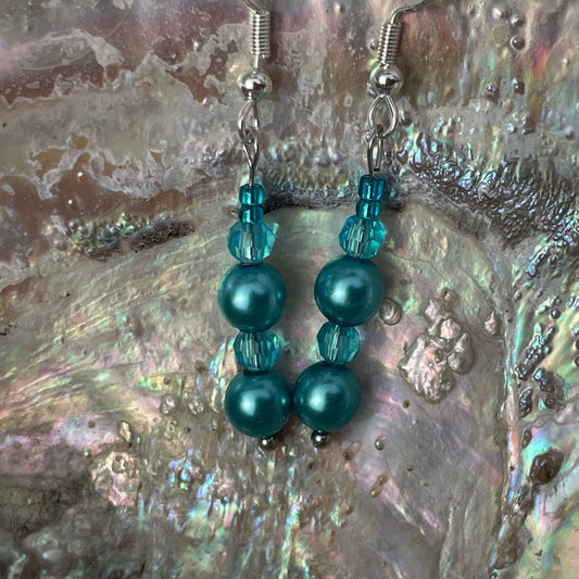 Crystal and pearl teal drop earrings close up with abalone shell background