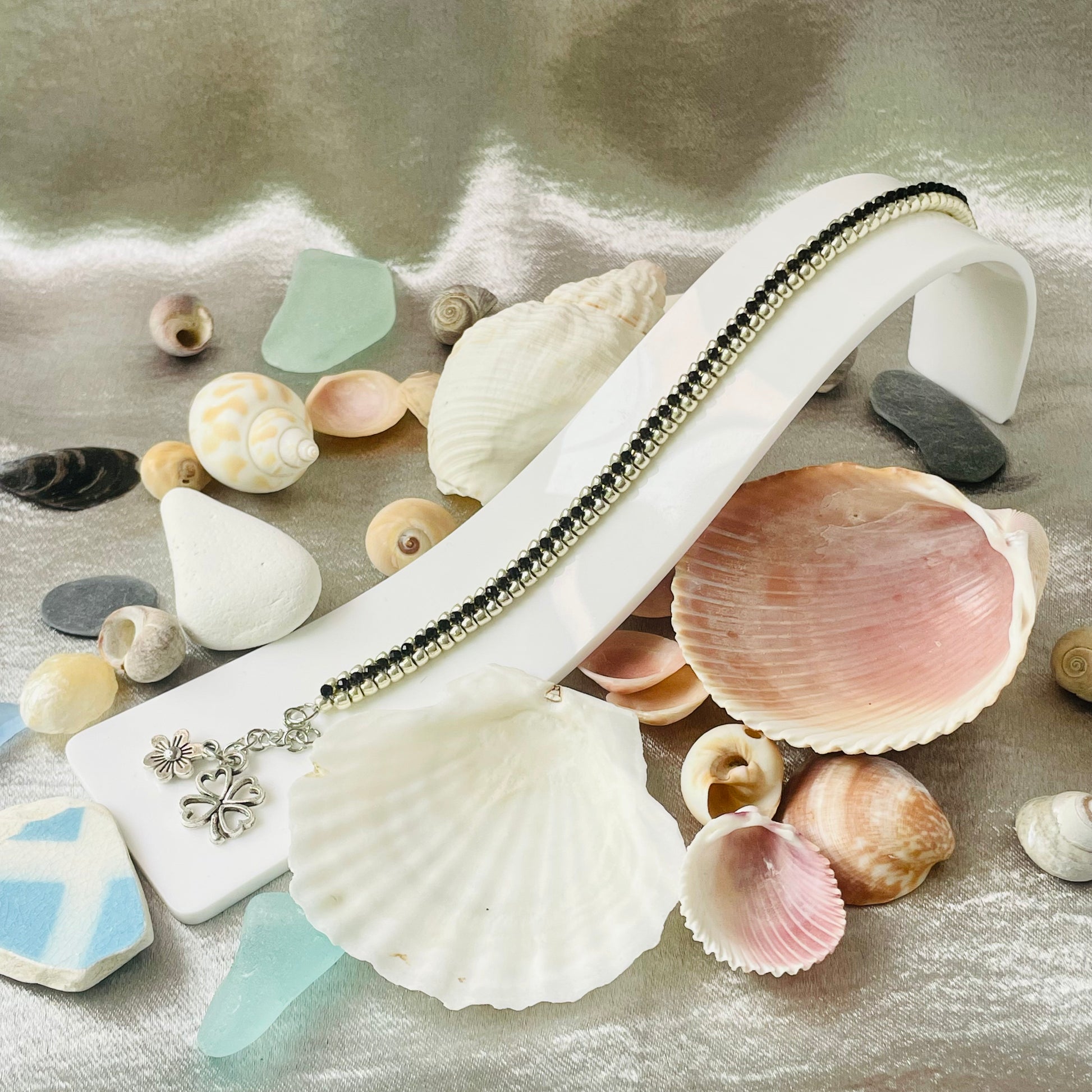 Seed bead and crystal bracelet on white stand surrounded by sea shells