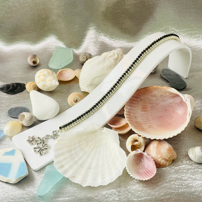 Seed bead and crystal bracelet on white stand surrounded by sea shells