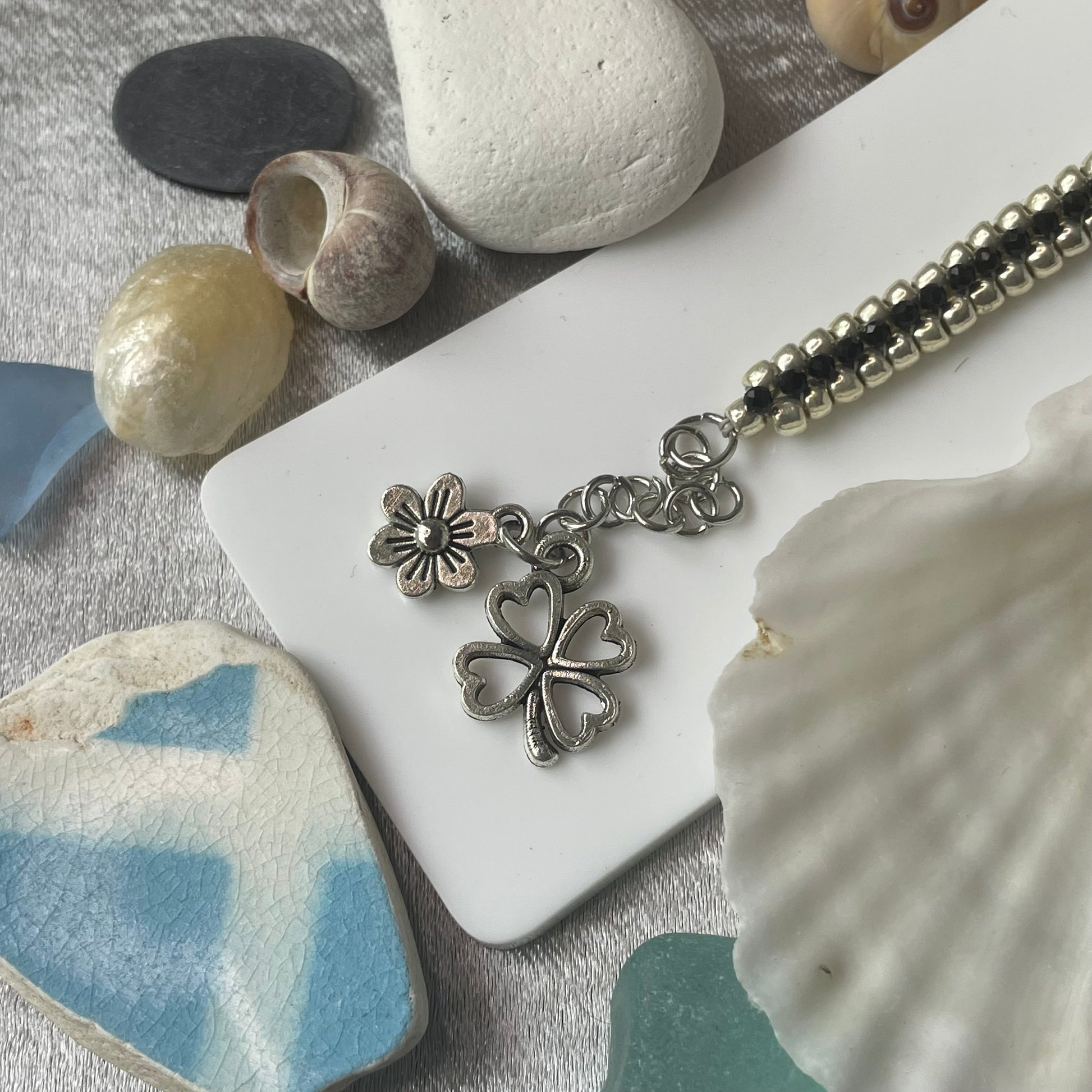 Seed bead and crystal bracelet on white stand with close up of charms