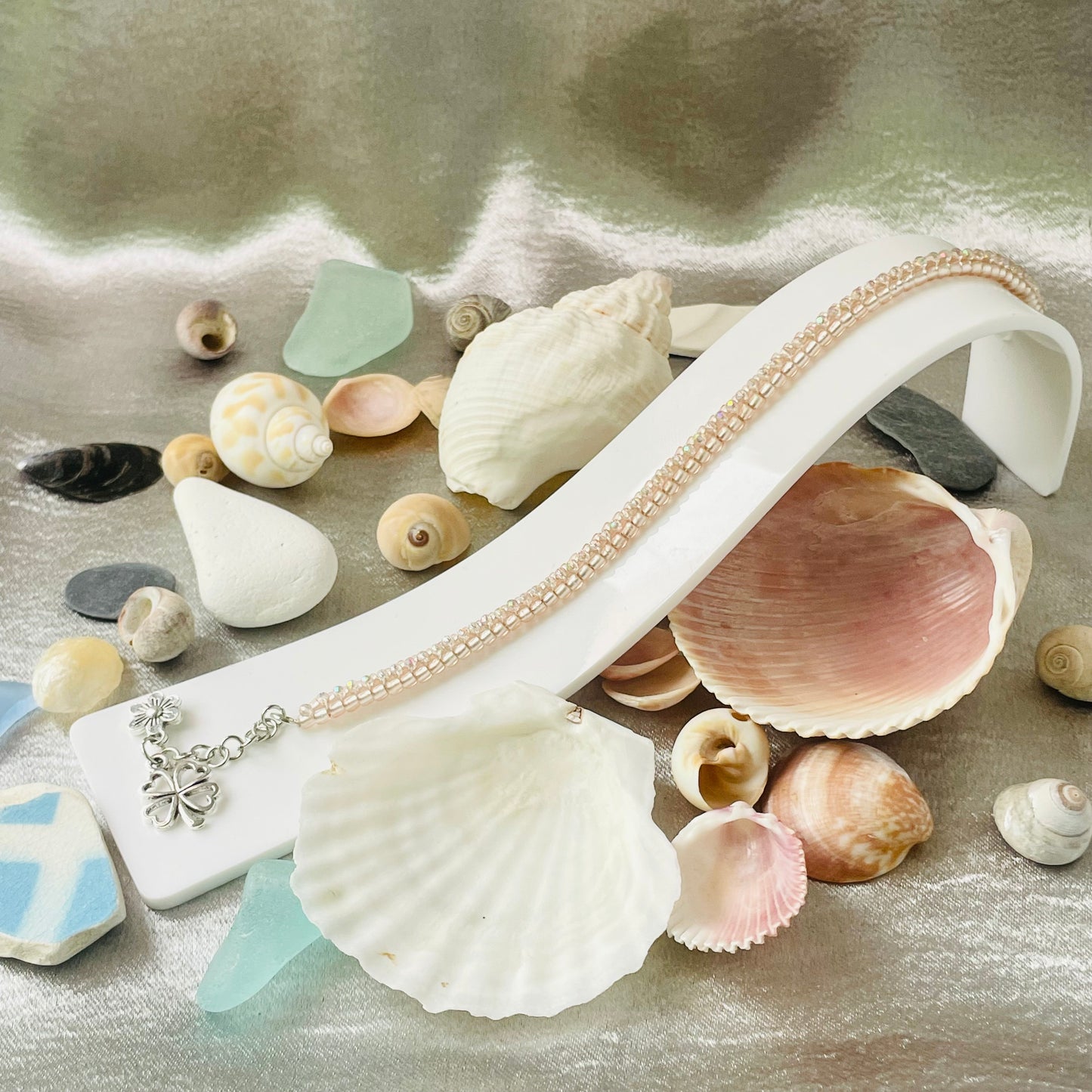 Seed bead and crystal bracelet on white stand surrounded by sea shells