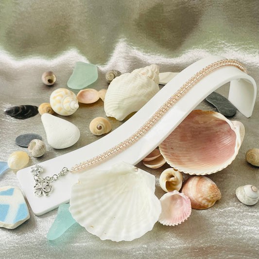 Seed bead and crystal bracelet on white stand surrounded by sea shells