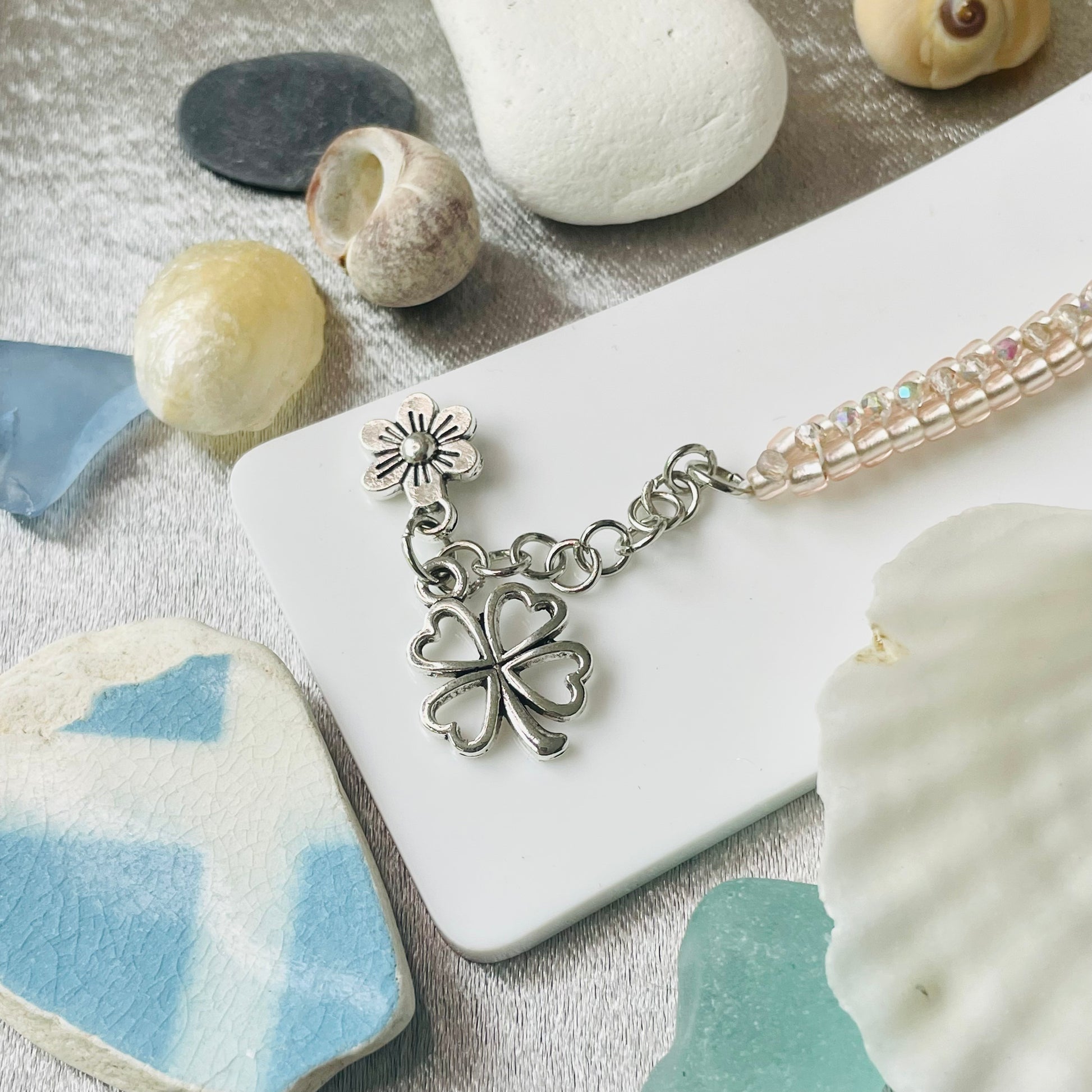 Seed bead and crystal bracelet on white stand with close up of charms