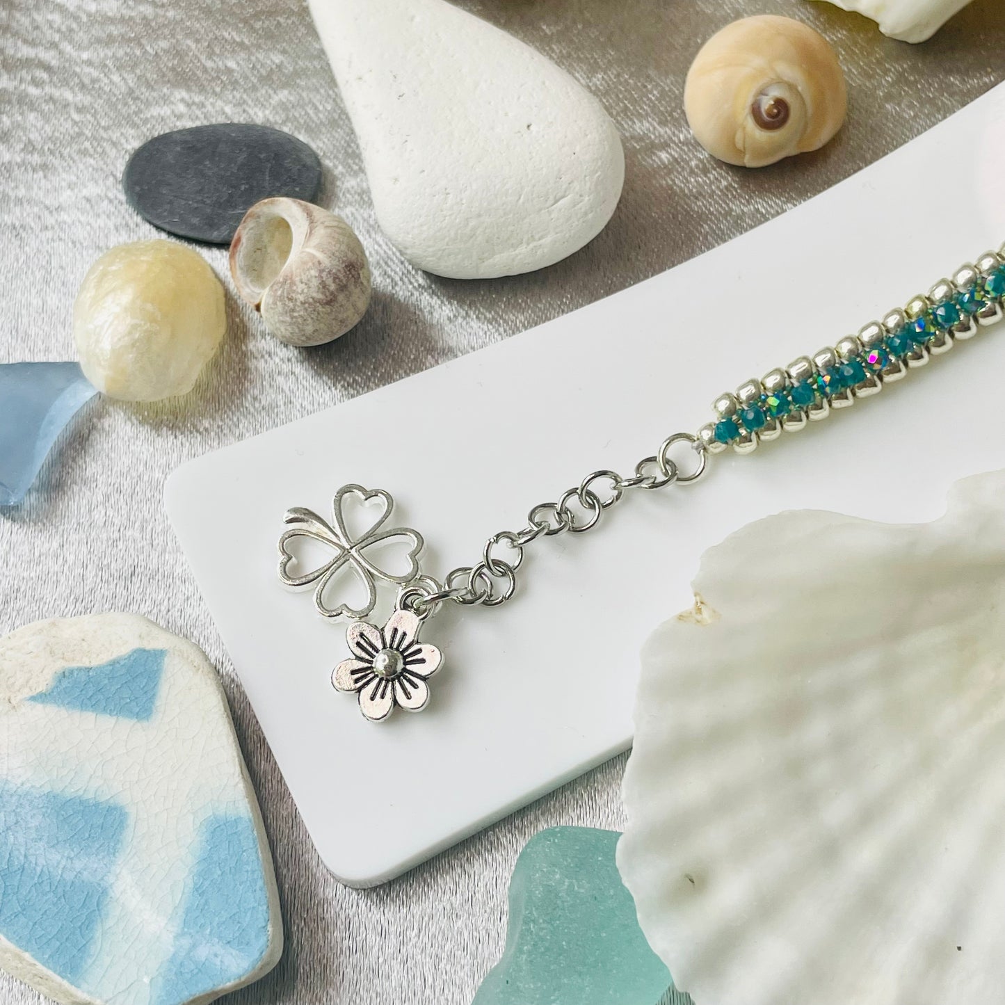 Seed bead and crystal bracelet on white stand with close up of charms