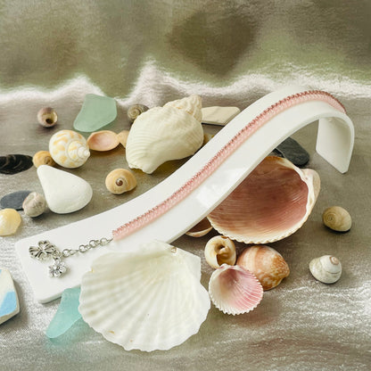 Seed bead and crystal bracelet on white stand surrounded by seashells