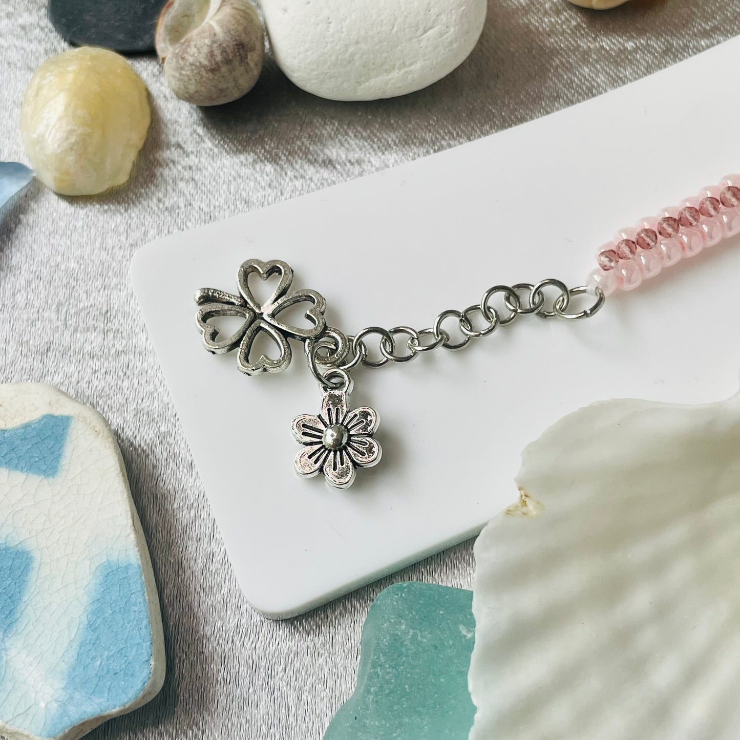 Seed bead and crystal bracelet on white stand showing charms