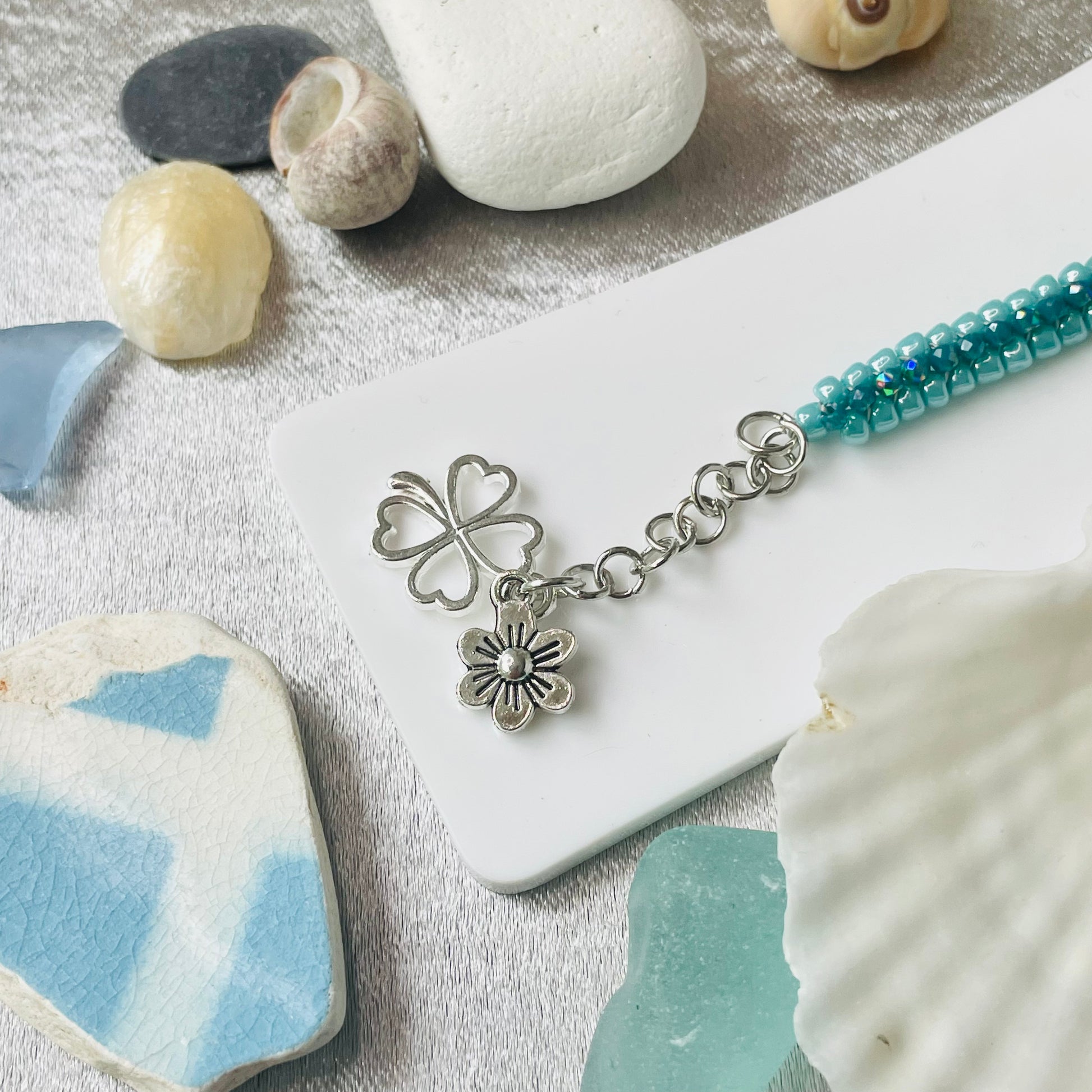 Seed bead and crystal bracelet on white stand with close up of charms