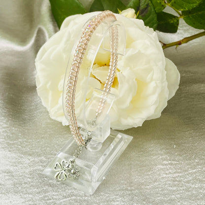 Seed bead and crystal bracelet on clear stand with white rose in background