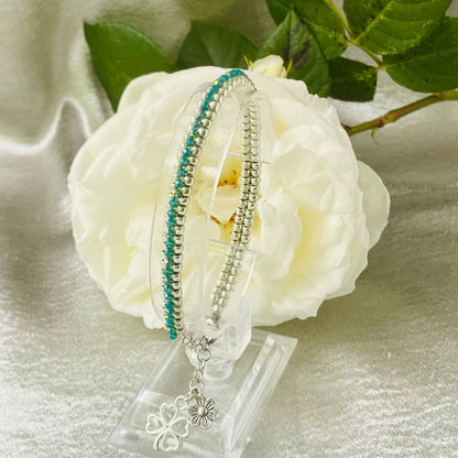 Seed bead and crystal bracelet on clear stand with white rose in background